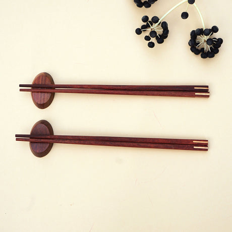 Experience the art of dining with a set of handmade wooden chopsticks with matching rests. Chopsticks and rests are handmade from wood with a natural wooden colour. Finished with a hand polish for a touch of a natural shine. Come in a set of 2 pairs of wooden square chopsticks with 2 wooden rests.   Suitable for hot or cold food. Ideal gift and home use. Handmade and fair trade product. 